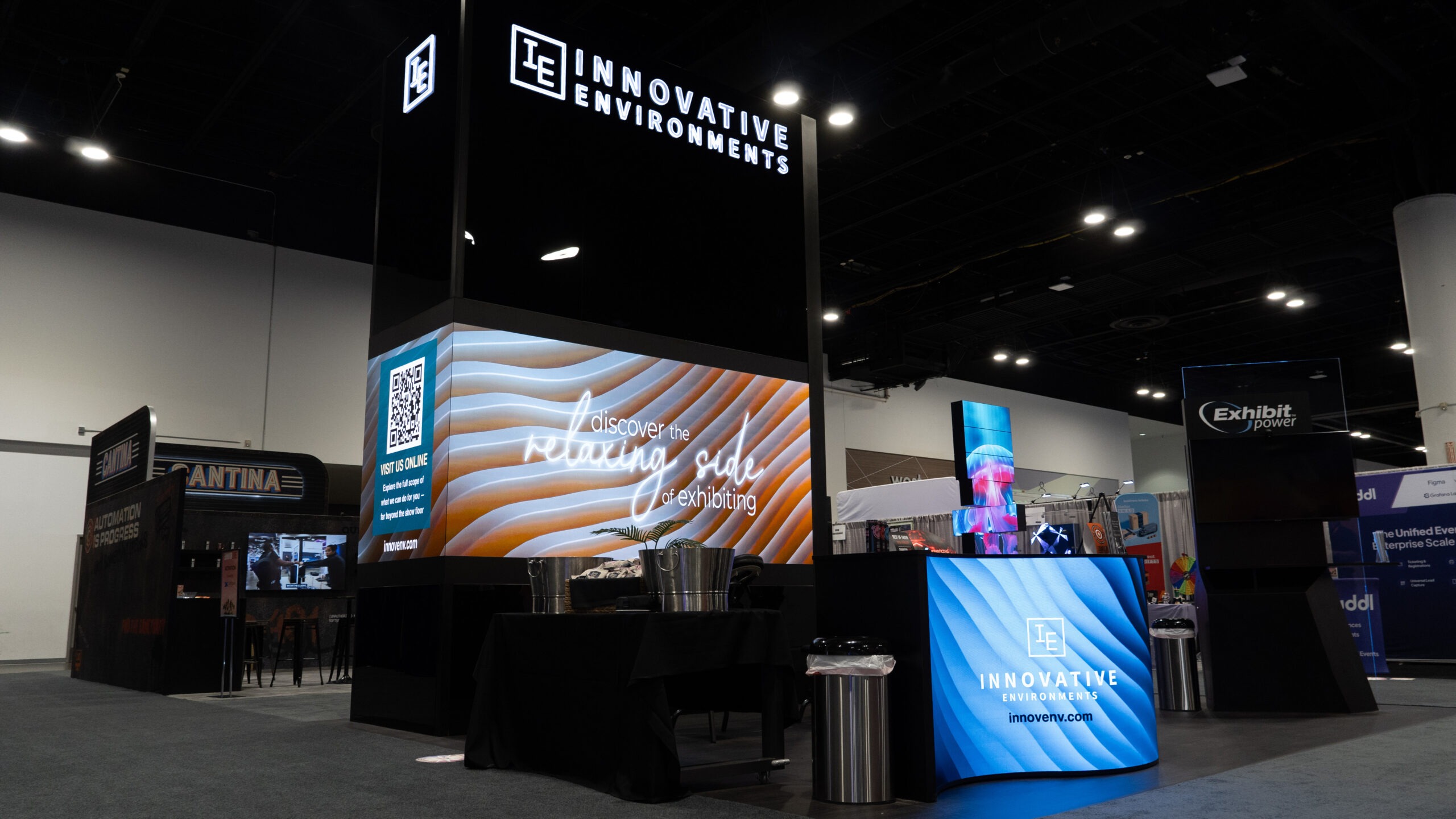 Attendees gathering inside the Innovative Environments booth at EXHIBITORLIVE